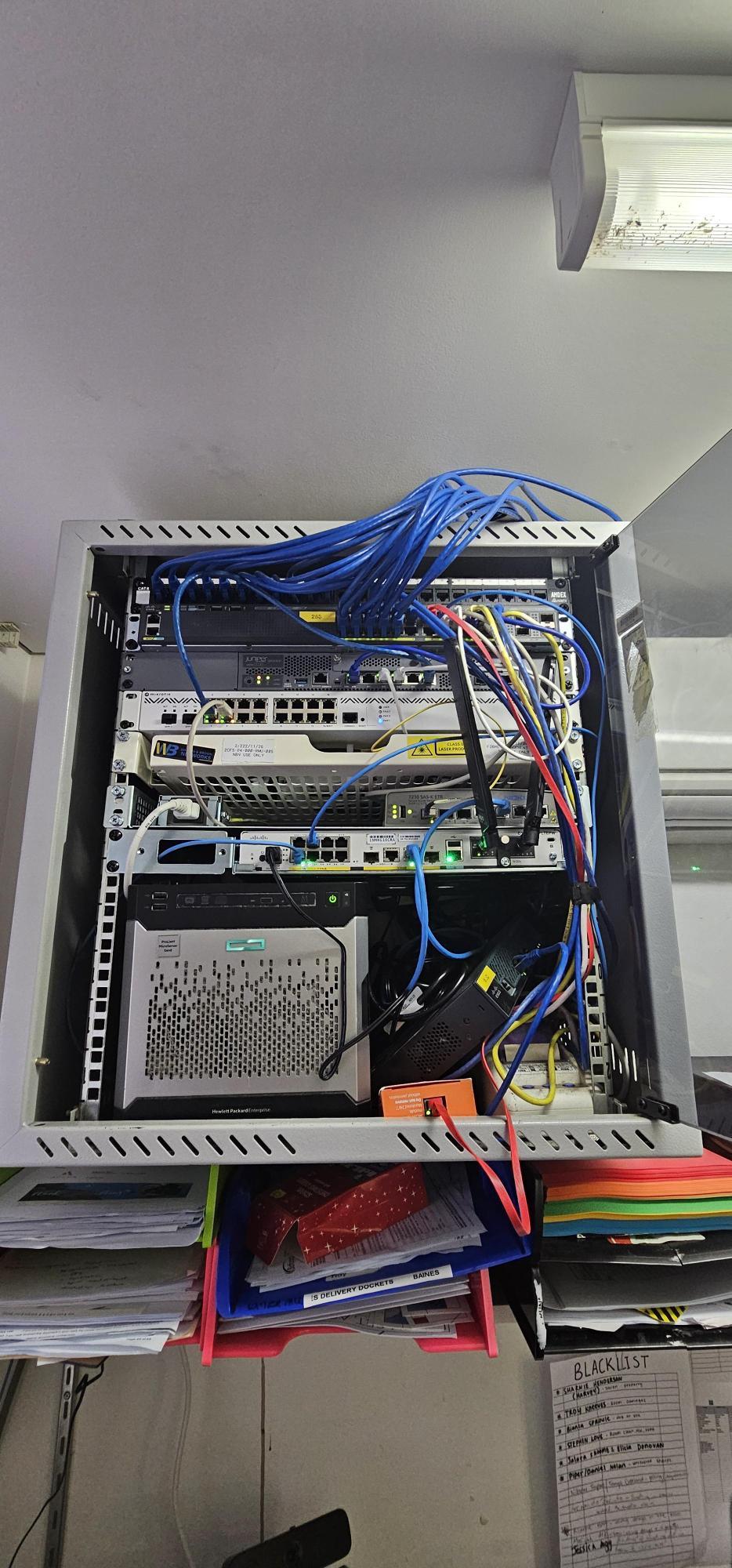Motel network rack before rebuild - tangled unlabelled patch leads running across switches and server